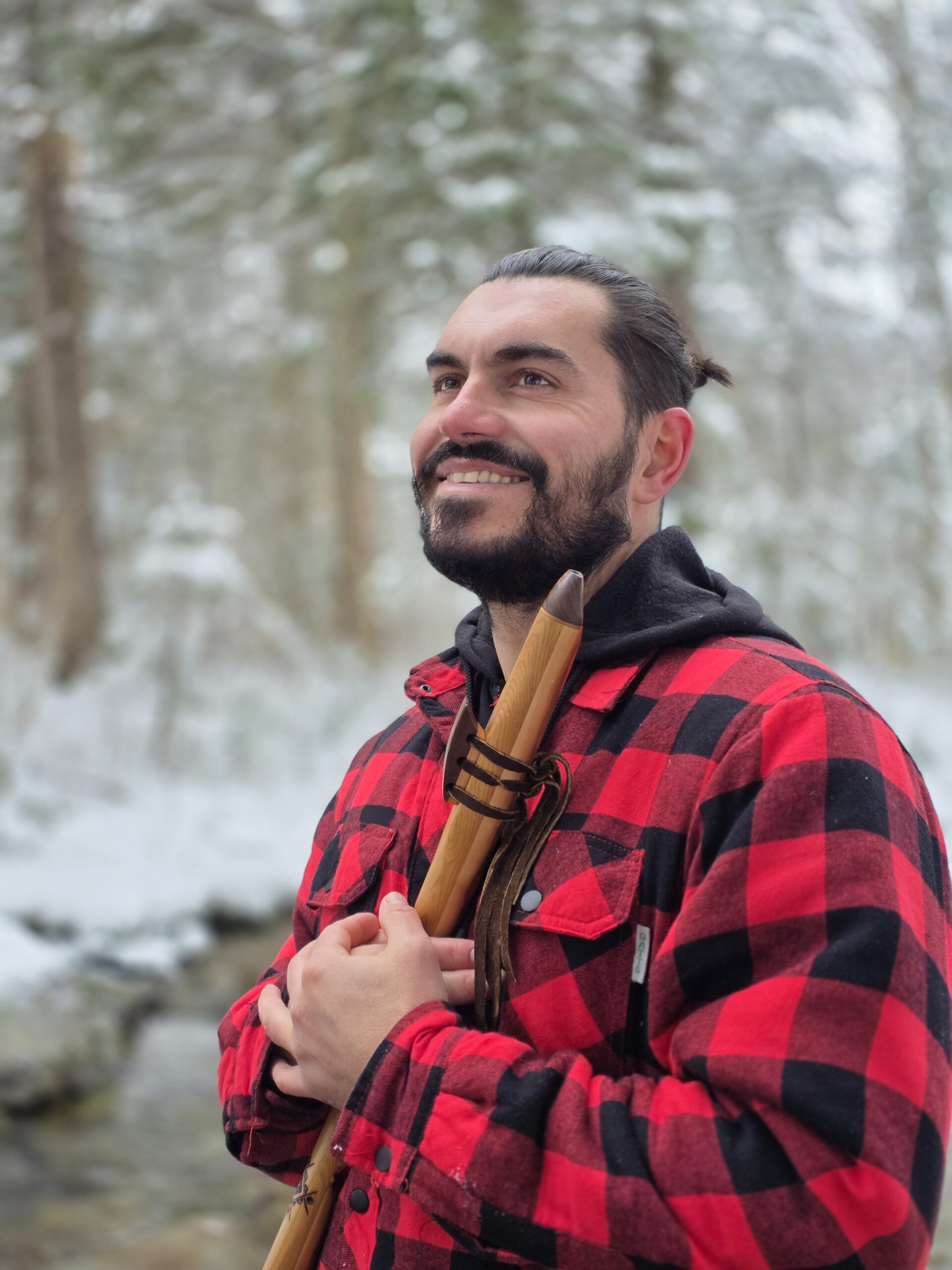 Homme souriant avec un bâton en bois dans la neige.