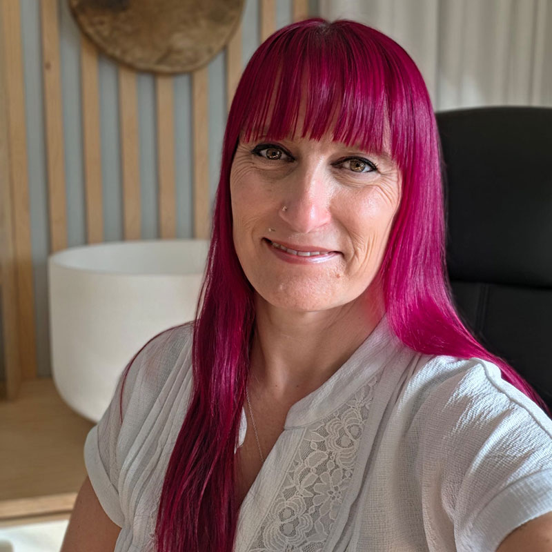 Femme avec cheveux roses souriante dans un bureau