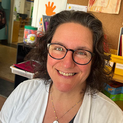 Femme souriante avec des lunettes dans une salle.