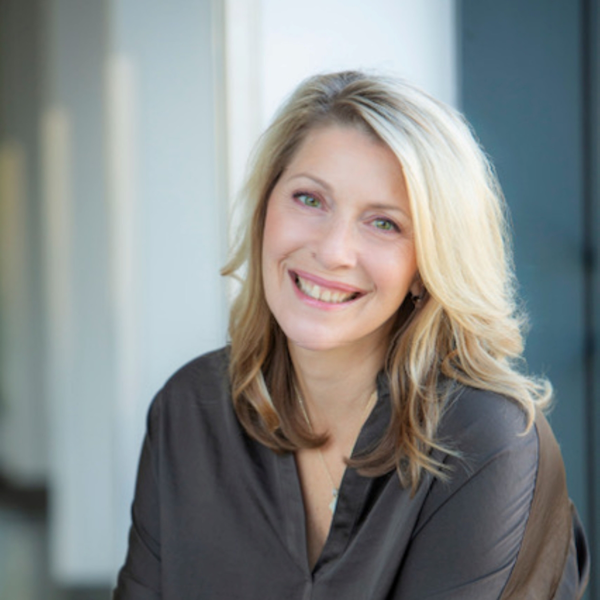 Portrait d’une femme blonde souriante en chemisier sombre