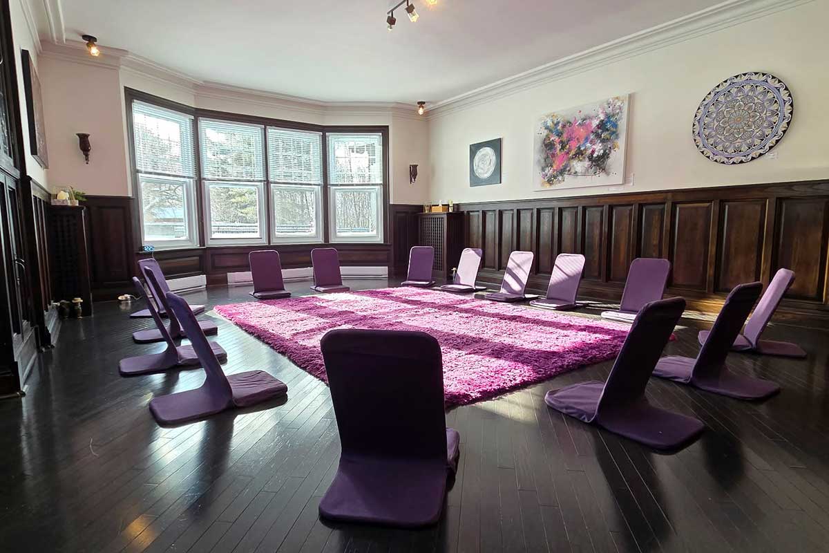 Salle de méditation avec tapis et chaises violettes.