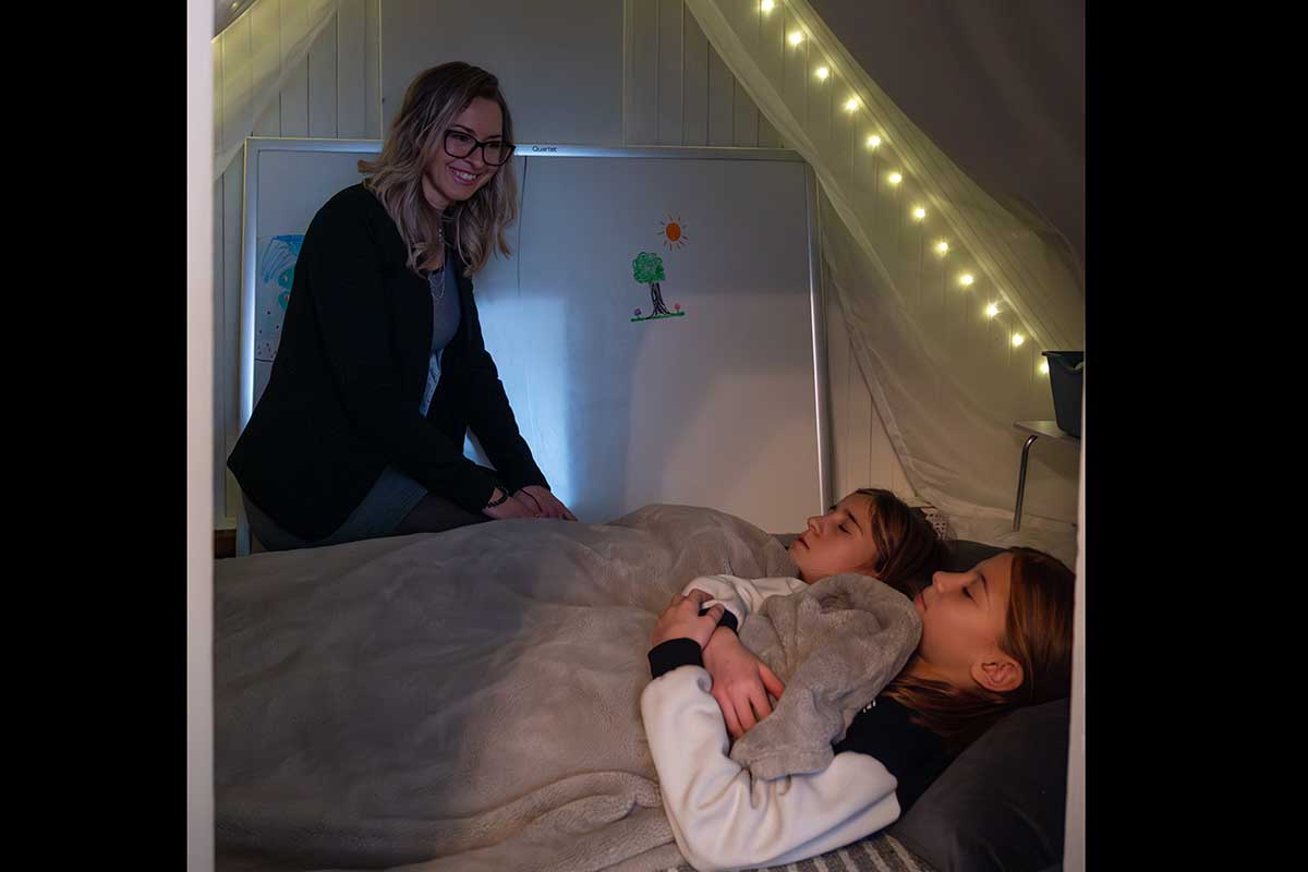 Femme veillant sur deux enfants au lit.