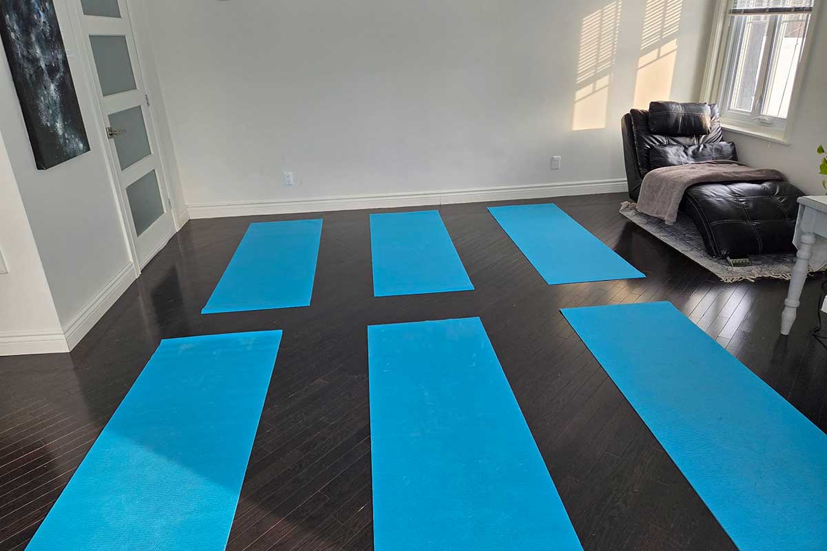 Salle de yoga avec tapis bleus alignés.